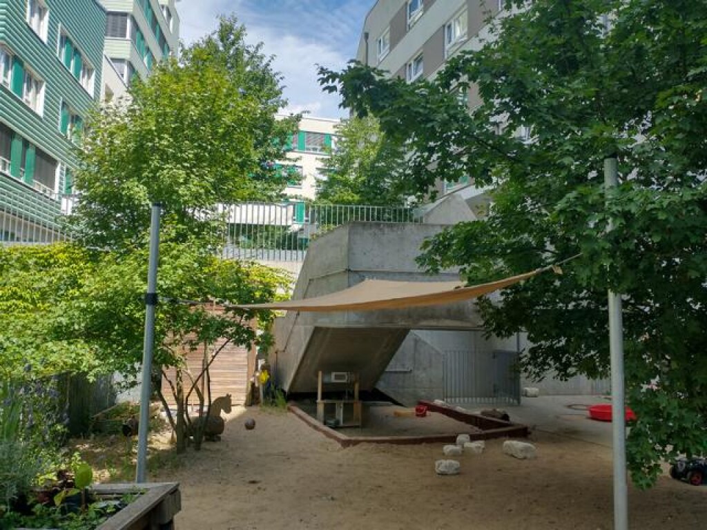 AWO Kita Am Inselpark Außengelände Krippenbereich mit Sandkasten und Sonnensegel.